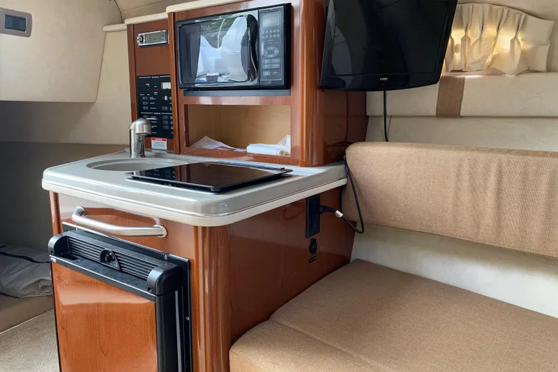 Slide: The Image of Interior of 2012 Sea Ray 240 Sundancer boat with kitchenette and seating area. - 34