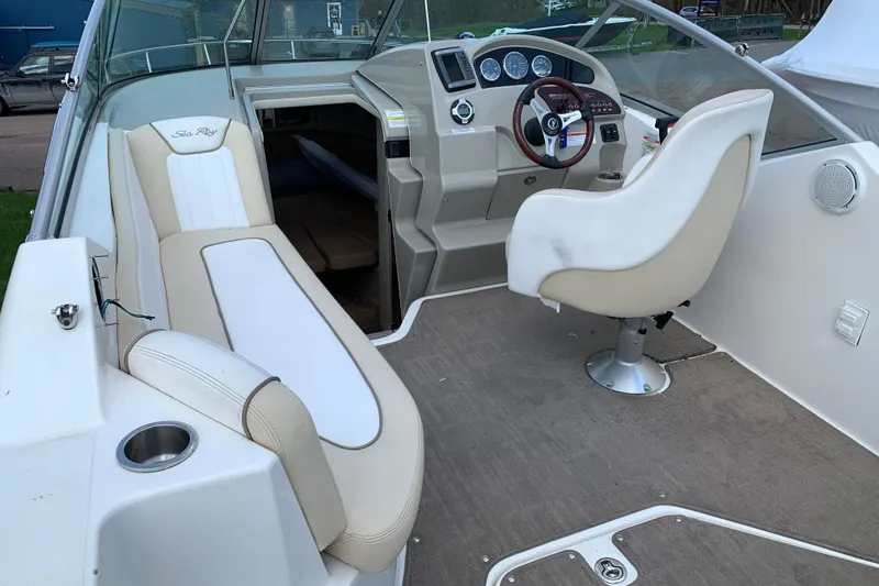 Slide: The Image of Interior of a 2012 Sea Ray 240 Sundancer boat with beige seating and steering console. - 6