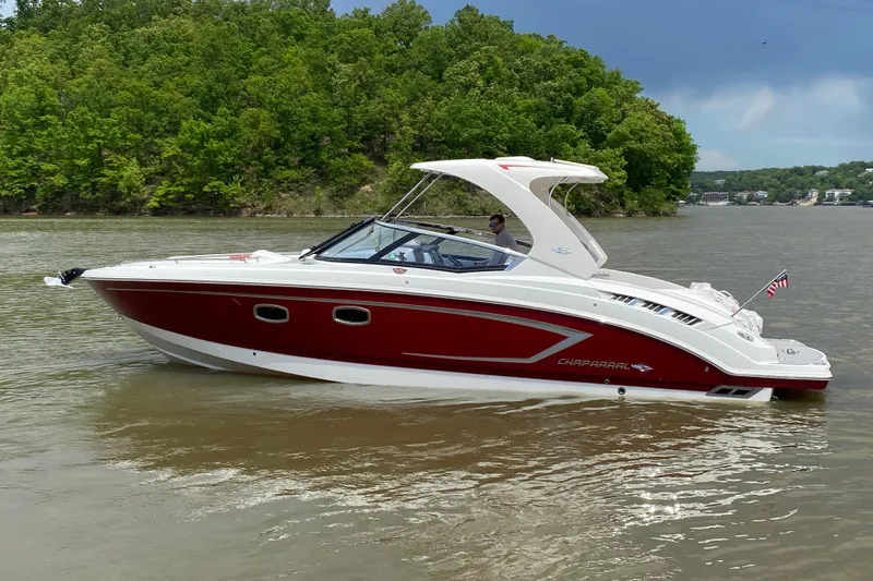 Slide: The Image of 2012 Chaparral 327 SSX boat cruising on a lake with lush green shoreline. - 3