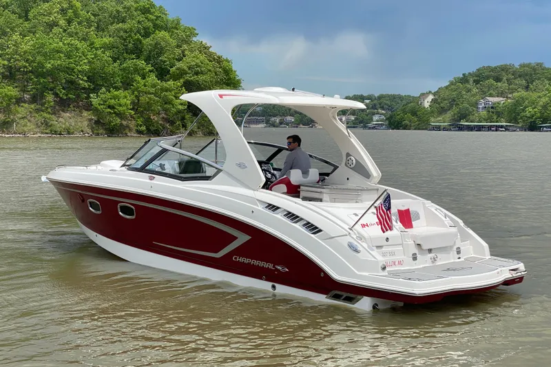 Slide: The Image of 2012 Chaparral 327 SSX boat cruising on a lake with lush green shoreline. - 4