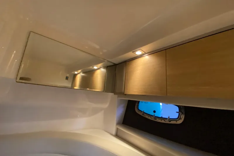 Slide: The Image of Interior of 2012 Chaparral 327 SSX boat with mirror, wooden cabinets, and porthole window. - 49