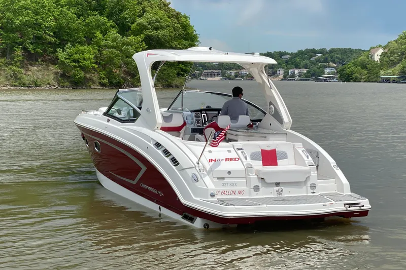 Slide: The Image of 2012 Chaparral 327 SSX boat cruising on a scenic lake with lush green surroundings. - 5