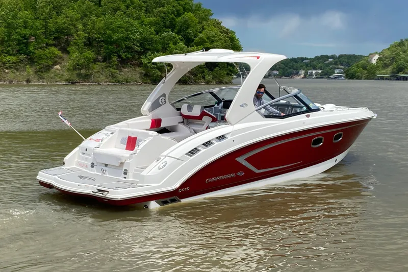 Slide: The Image of 2012 Chaparral 327 SSX boat cruising on a scenic lake with lush green shoreline. - 7