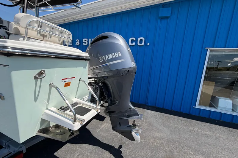 Slide: The Image of 2016 Parker 2100 Center Console boat with Yamaha outboard motor, parked near blue building. - 25