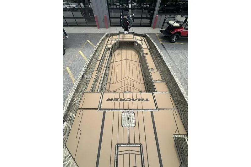 Slide: The Image of 2026 Tracker Grizzly 1756 T Marsh boat with camouflage design, parked outdoors. - 11