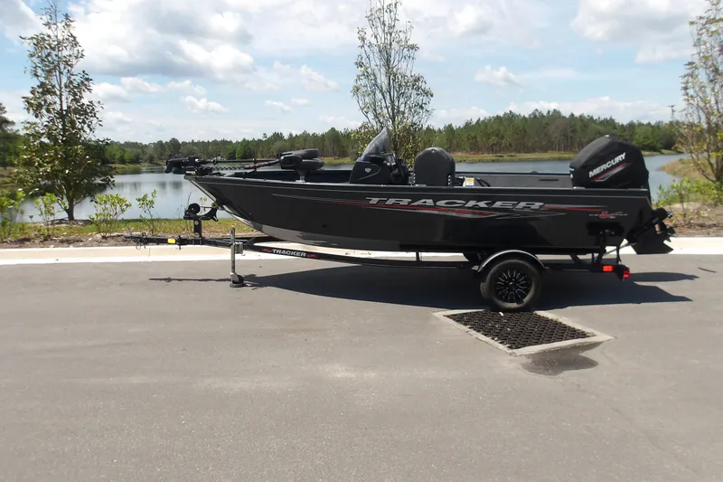 The Image of 2021 Tracker Pro Guide V-16 SC boat on trailer by a scenic lake. - 0