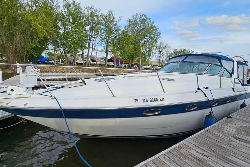 The Image of 1988 Regal Commodore 360 boat docked at marina, surrounded by trees and clear sky. - 1