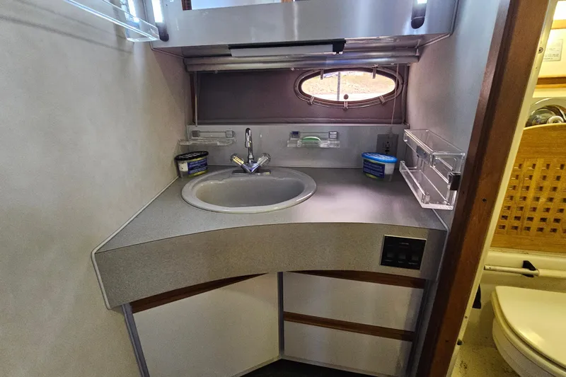 Slide: The Image of Bathroom sink area in a 1988 Regal Commodore 360 boat, featuring storage and porthole. - 21