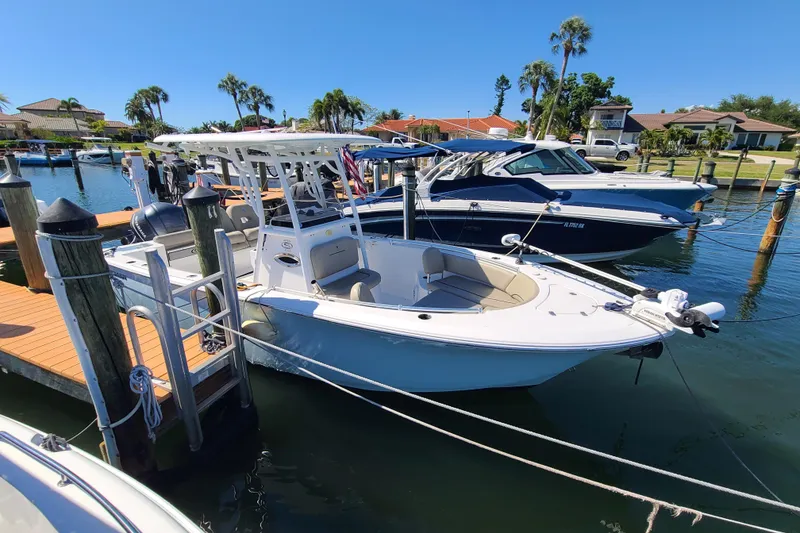 The Image of 2021 Sportsman Open 242 Center Console boat docked in a sunny marina. - 0