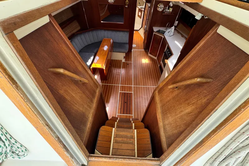 Slide: The Image of Interior view of 1990 Catalina 42 MkII sailboat, featuring wooden stairs and cozy seating area. - 12