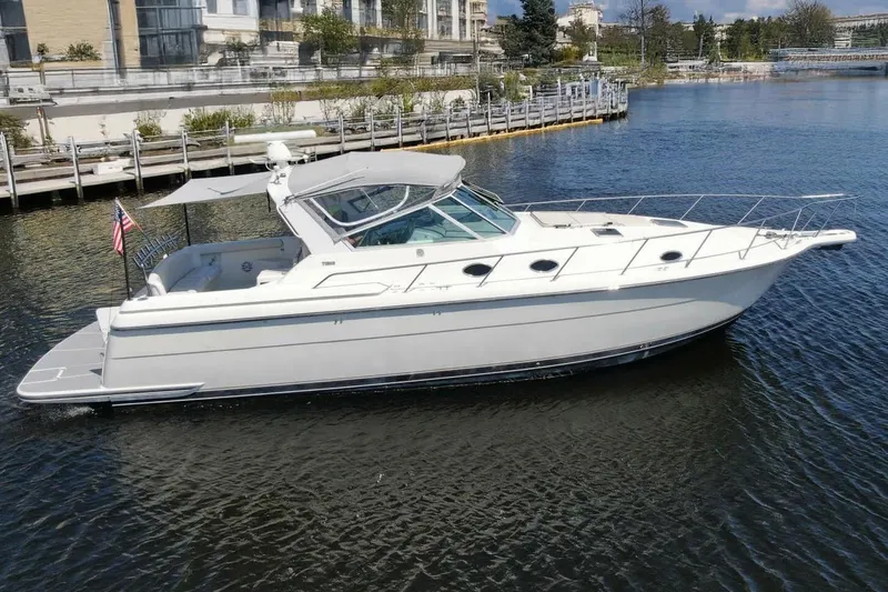 Slide: The Image of 1995 Tiara Yachts 4000 Express cruising on a calm waterfront near a marina. - 1