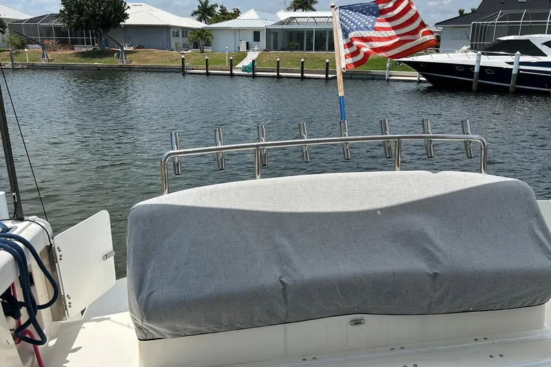Slide: The Image of 1995 Tiara Yachts 4000 Express with American flag, docked in a serene canal setting. - 10