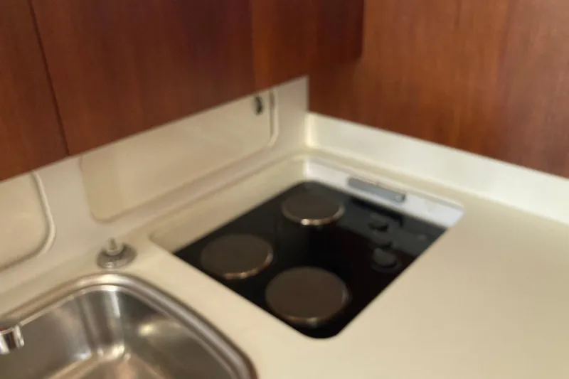 Slide: The Image of 1995 Tiara Yachts 4000 Express kitchen with stove and sink, featuring wooden cabinetry. - 14