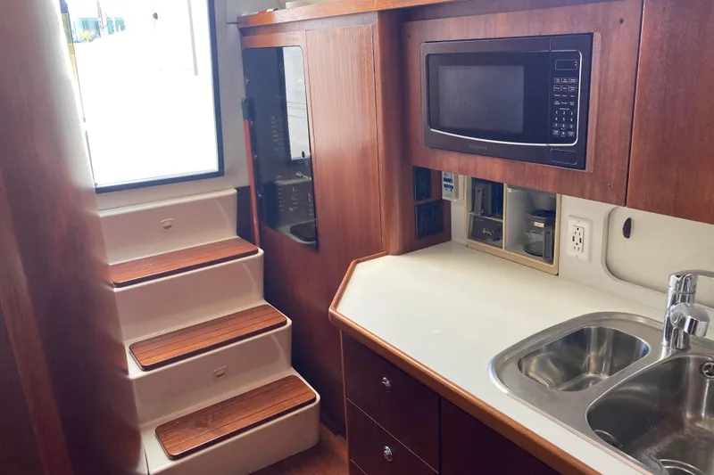 Slide: The Image of 1995 Tiara Yachts 4000 Express interior with kitchenette, microwave, sink, and wooden steps. - 15