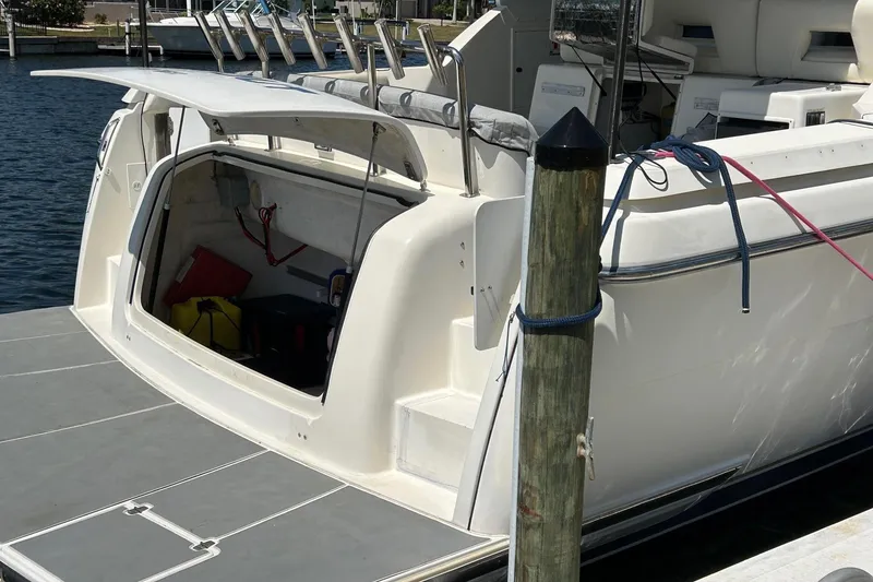 Slide: The Image of 1995 Tiara Yachts 4000 Express docked, open storage compartment, fishing rod holders visible. - 3