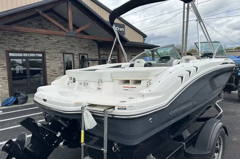Slide: The Image of 2018 Chaparral 19 H2O Sport boat on trailer, parked outside a building. - 18