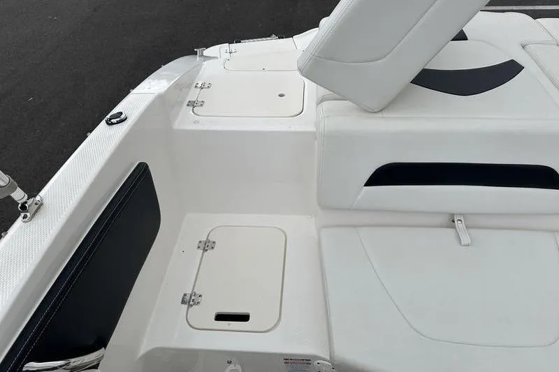 Slide: The Image of 2018 Chaparral 19 H2O Sport boat interior with white seating and storage compartments. - 19