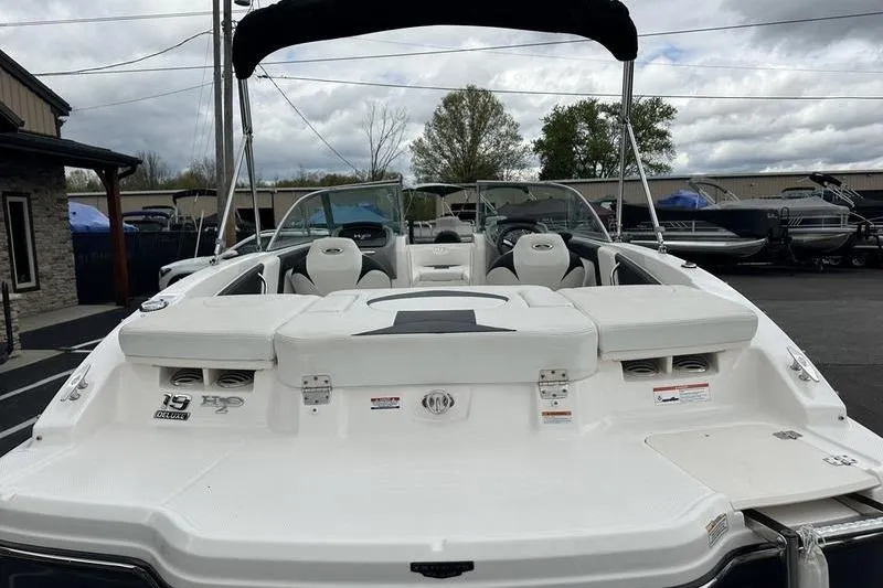 Slide: The Image of 2018 Chaparral 19 H2O Sport boat with white seating and black canopy, parked outdoors. - 20
