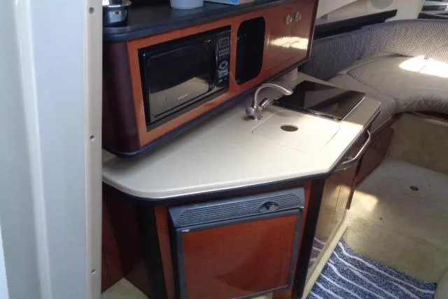Slide: The Image of 2005 Sea Ray Sundancer 260 interior with kitchenette, microwave, sink, and cozy seating area. - 17