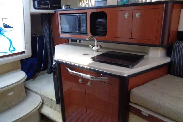 Slide: The Image of 2005 Sea Ray Sundancer 260 interior kitchen with microwave, sink, and stove. - 18