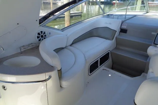 Slide: The Image of 2005 Sea Ray Sundancer 260 interior with white seating and compact kitchenette. - 8