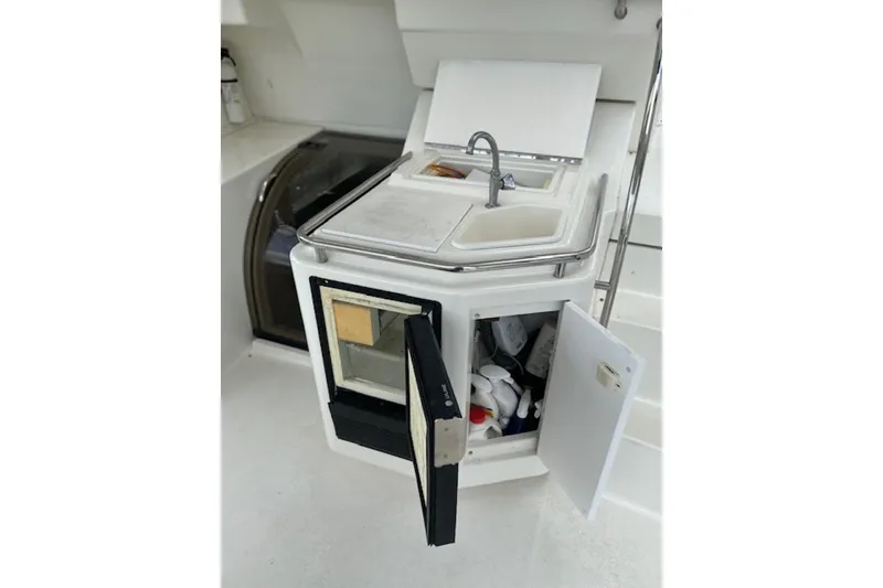 Slide: The Image of 1996 Silverton 442 Cockpit Motor Yacht kitchenette with sink, storage, and mini-fridge. - 11