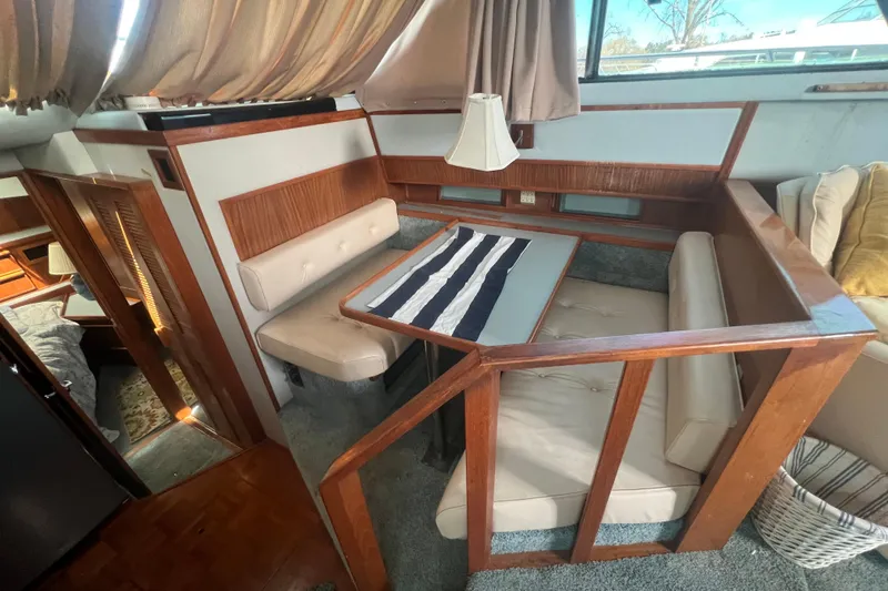 Slide: The Image of 1987 Sea Ray 410 Aft Cabin interior with cozy dining area and wood accents. - 12