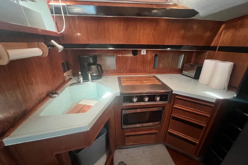 Slide: The Image of 1987 Sea Ray 410 Aft Cabin kitchen with wood cabinetry, sink, stove, and appliances. - 13