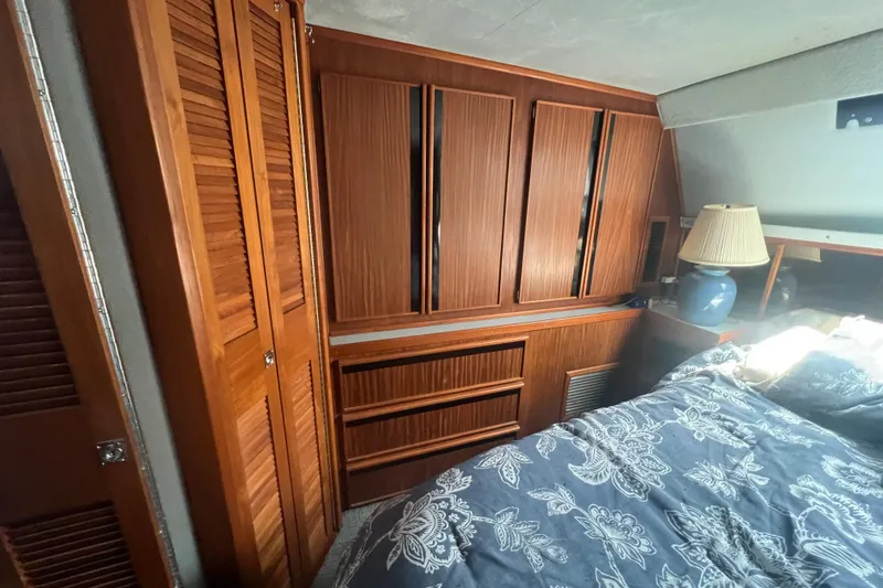 Slide: The Image of 1987 Sea Ray 410 Aft Cabin interior with wooden cabinets and floral bedding. - 19
