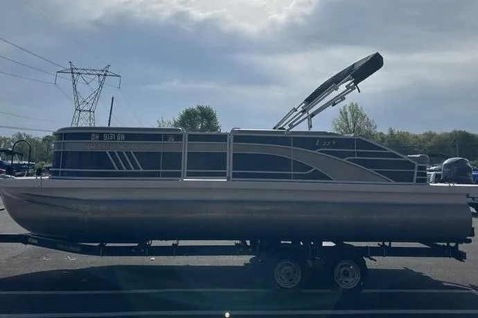 Slide: The Image of 2022 Bennington 22 L pontoon boat on trailer, parked outdoors under cloudy sky. - 19