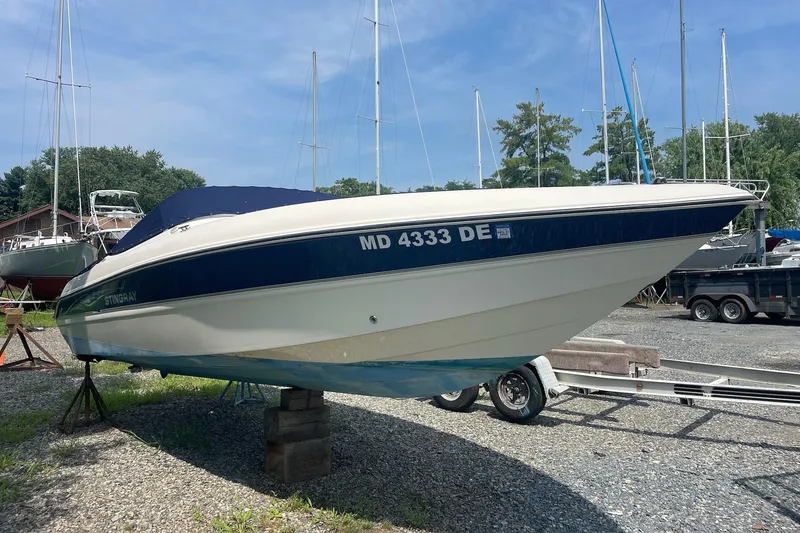 Slide: The Image of 2006 Stingray 230 LX boat on trailer in a marina setting. - 2
