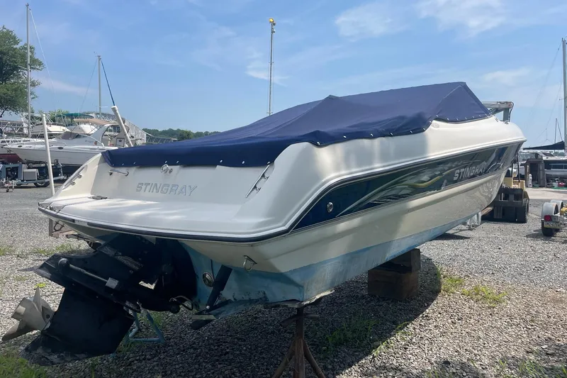 Slide: The Image of 2006 Stingray 230 LX boat with blue cover, parked on gravel lot. - 4