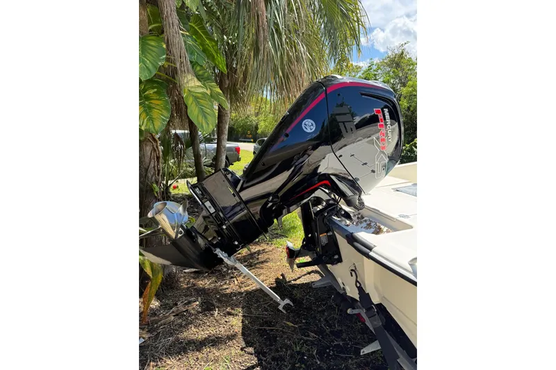 Slide: The Image of 2025 Mako Pro Skiff 19 CC with Mercury Pro XS engine, parked near tropical foliage. - 16
