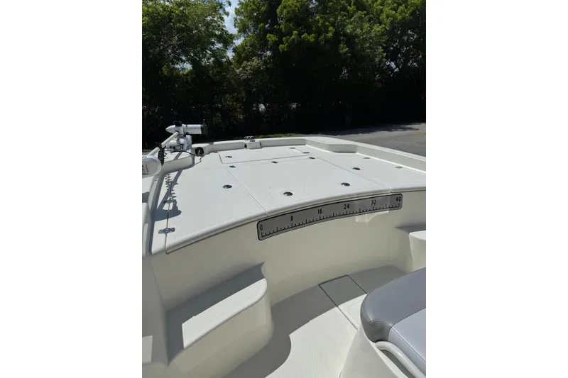 Slide: The Image of 2025 Mako Pro Skiff 19 CC boat deck with ruler, surrounded by trees. - 22
