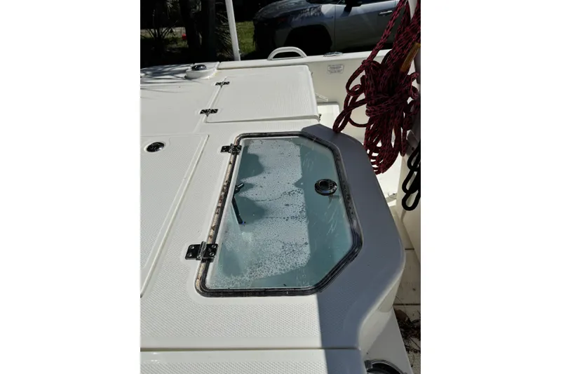 Slide: The Image of 2025 Mako Pro Skiff 19 CC boat deck with storage compartment and coiled rope. - 8