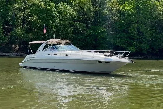 The Image of 2001 Sea Ray 410 Sundancer yacht cruising on a serene lake with lush green trees. - 0