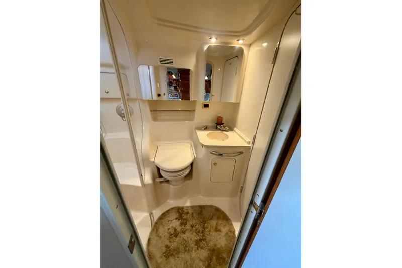 Slide: The Image of 2001 Sea Ray 410 Sundancer bathroom with toilet, sink, mirror, and beige decor. - 18
