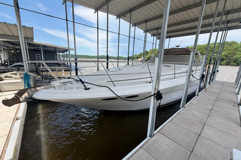 Slide: The Image of 2001 Sea Ray 410 Sundancer docked under a covered marina on a sunny day. - 2