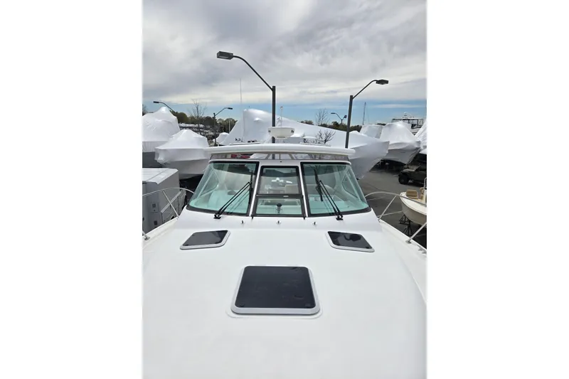Slide: The Image of 2006 Tiara Yachts 3200 Open boat docked, surrounded by covered vessels under cloudy sky. - 12