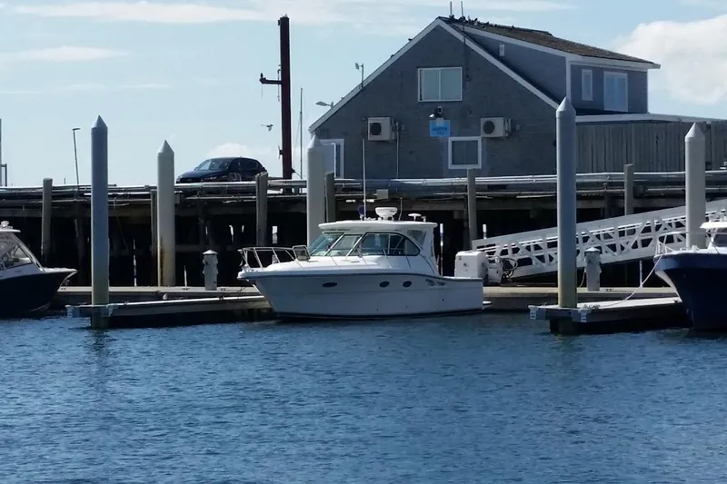 Slide: The Image of 2006 Tiara Yachts 3200 Open docked at a marina with a coastal building backdrop. - 2