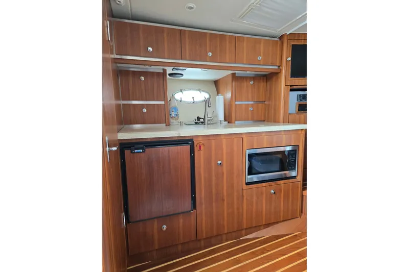 Slide: The Image of 2006 Tiara Yachts 3200 Open interior kitchen with wood cabinetry, microwave, and compact fridge. - 42