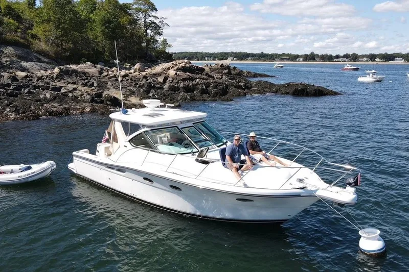 Slide: The Image of 2006 Tiara Yachts 3200 Open anchored near rocky shoreline, with two people relaxing on deck. - 7