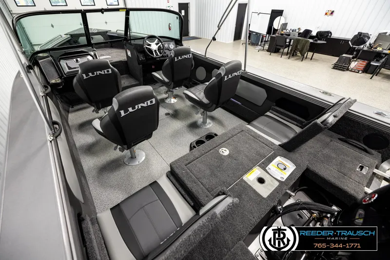 Slide: The Image of 2026 Lund 1875 Tyee boat interior with seating and steering wheel in showroom. - 10