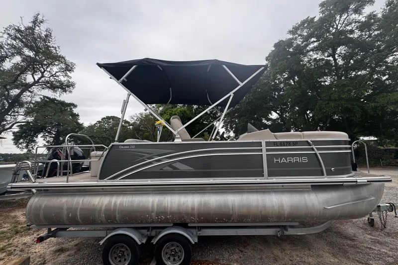 The Image of 2020 Harris Cruiser 210 pontoon boat with canopy on trailer, parked outdoors. - 1