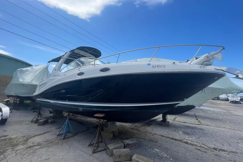 The Image of 2007 Sea Ray Sundancer 260 boat on stands in a marina under a clear blue sky. - 2