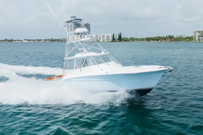 Slide: The Image of 2019 Custom Carolina Daniels Boatworks cruising on open water, with coastal buildings in the background. - 3