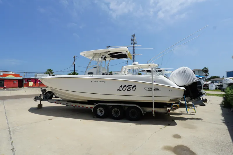 The Image of 2004 Boston Whaler 320 Outrage boat on trailer in sunny marina setting. - 0