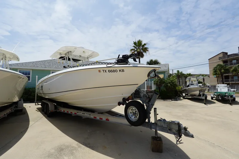 Slide: The Image of 2004 Boston Whaler 320 Outrage boat on trailer, parked outdoors under a clear sky. - 2