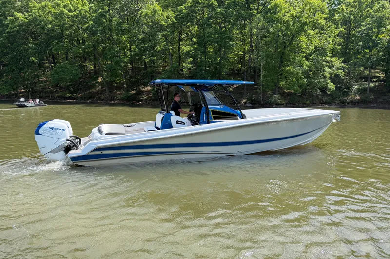 Slide: The Image of 2020 Nor-Tech 340 Sport Center Console boat cruising on a lake with lush green trees. - 5