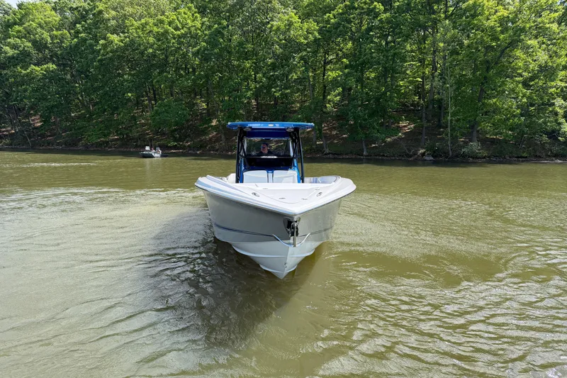 Slide: The Image of 2020 Nor-Tech 340 Sport Center Console boat cruising on a calm lake with forest backdrop. - 6